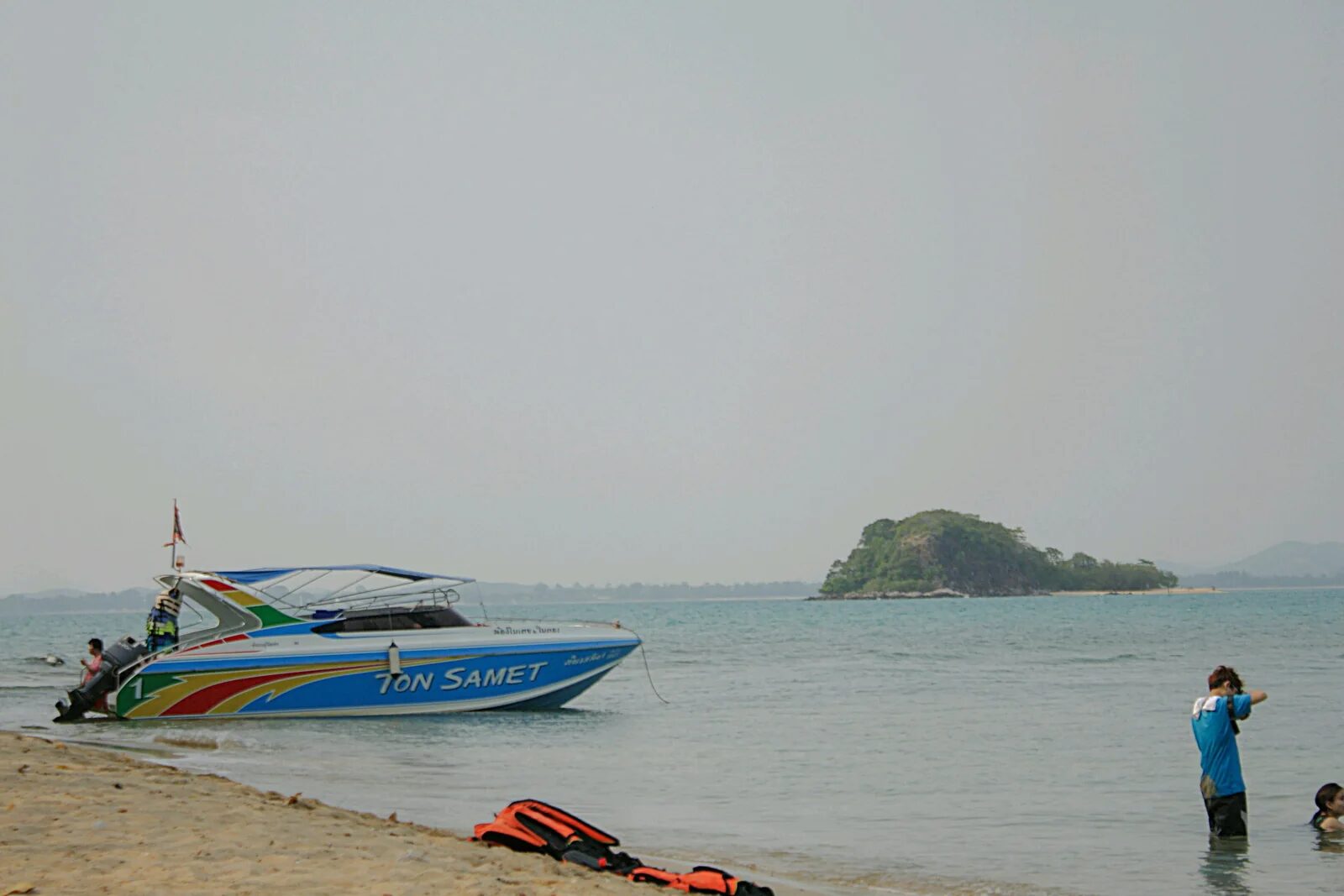 A speedboat and travellers beside a Koh Samet beach