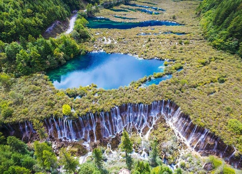 Blue lake and broad waterfall among the forests of Jiuzhaigou Valley