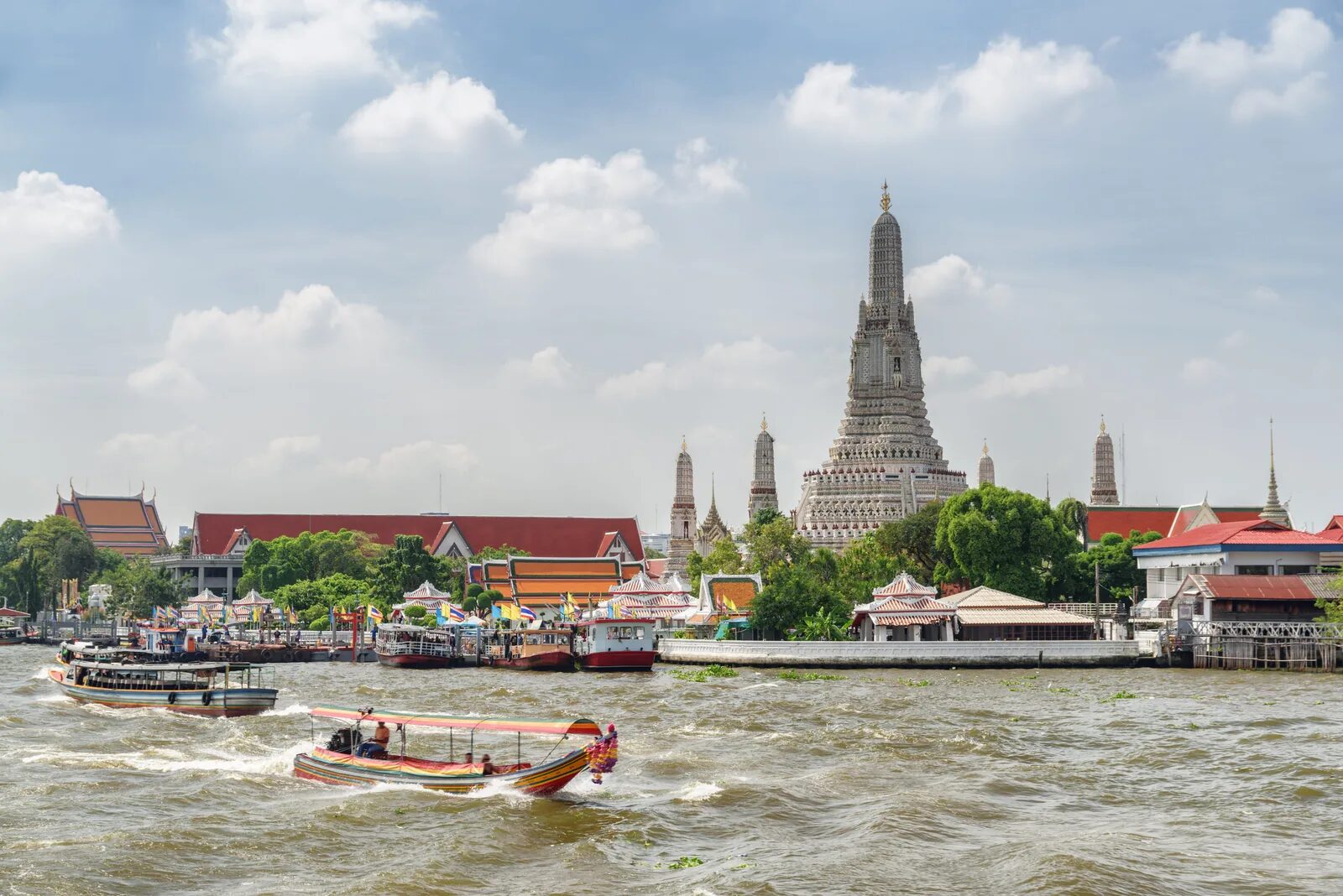 Wat Arun on the bank of the Chao Phraya River in Bangkok with boats passing