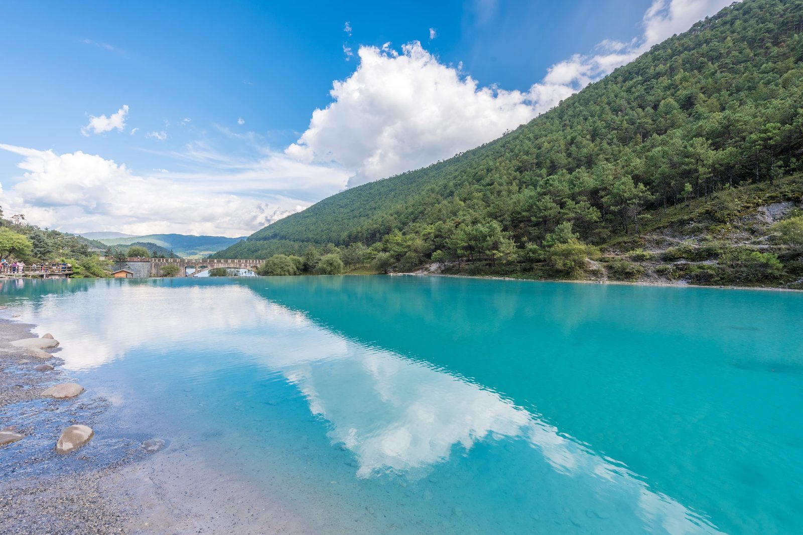 Clear blue-green water of Blue Moon Valley with pine-covered slopes