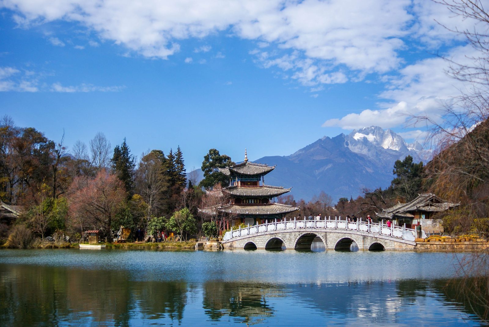 Arched bridge and pavilions at Black Dragon Pool with Jade Dragon Snow Mountain beyond