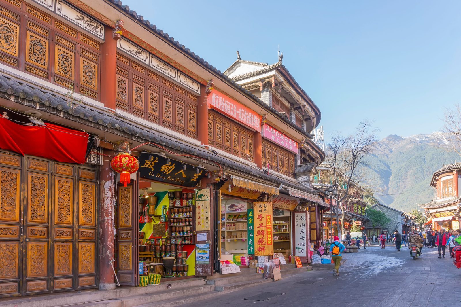 Shopfronts with carved wooden doors in Dali Ancient Town and snow mountains beyond