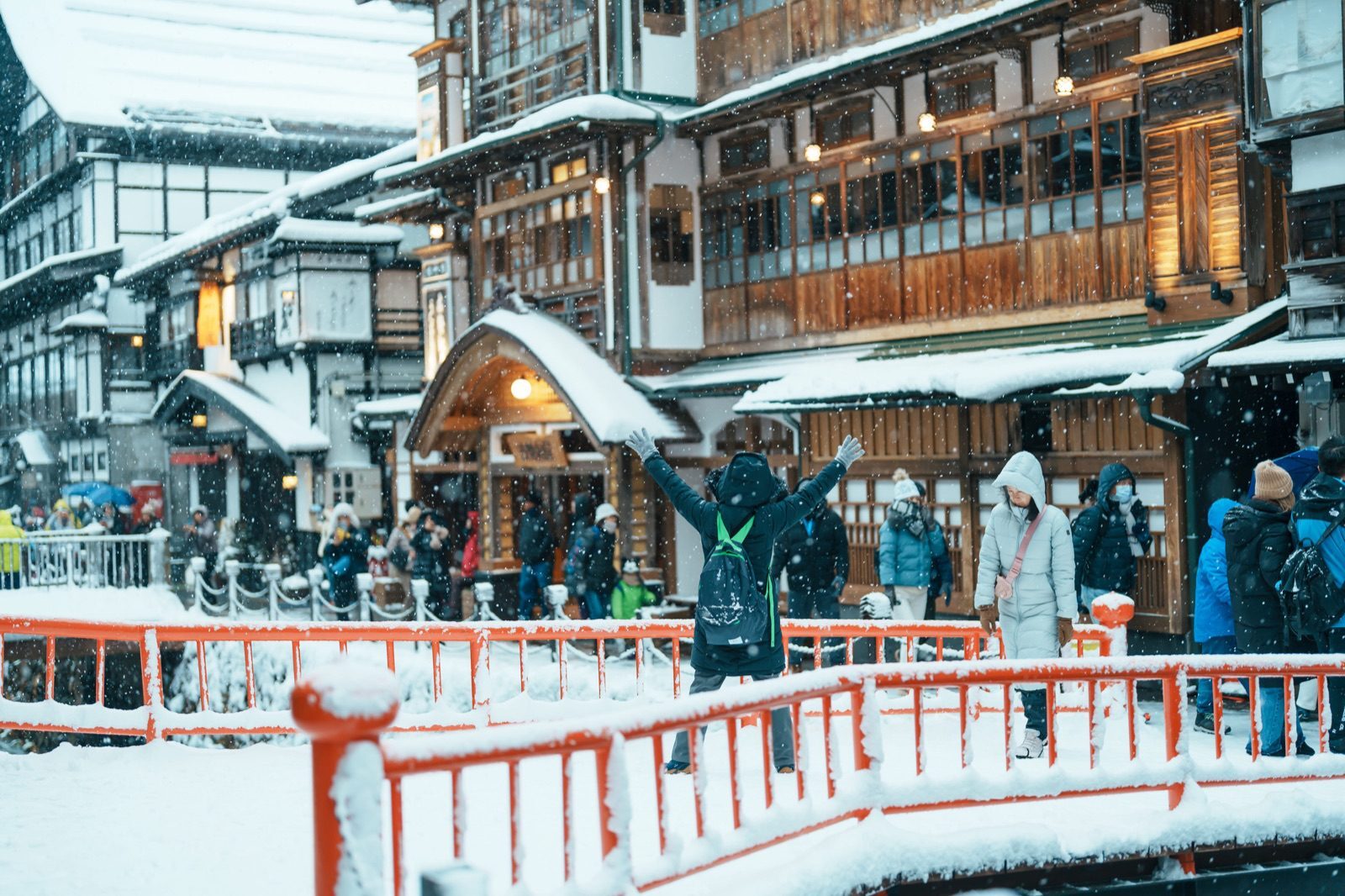 Red bridge and wooden inns of Ginzan Onsen in falling snow